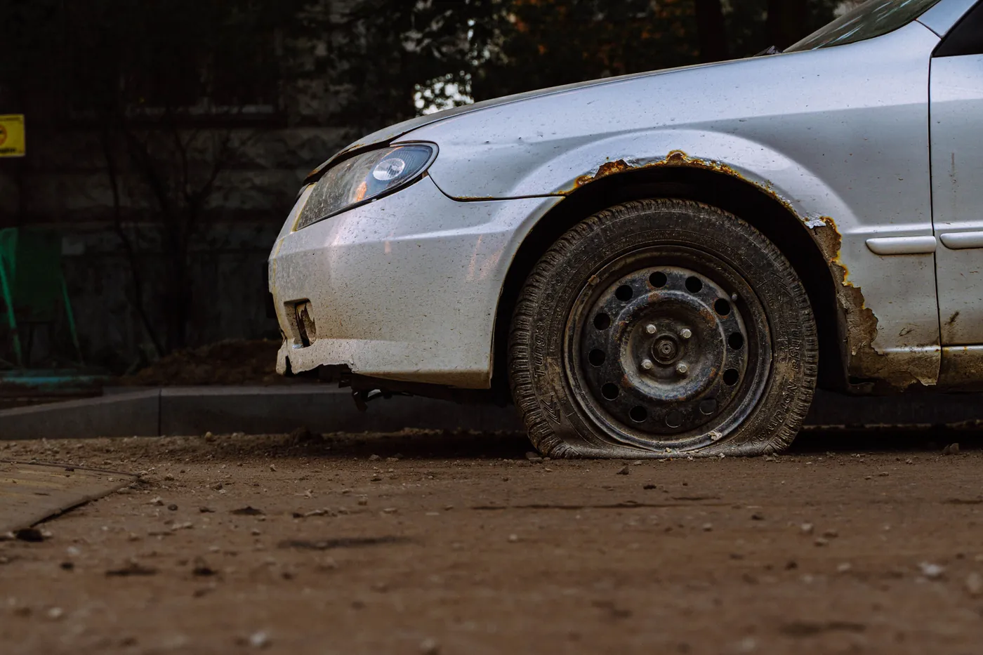 A silver sedan with a flat front tyre on the shoulder