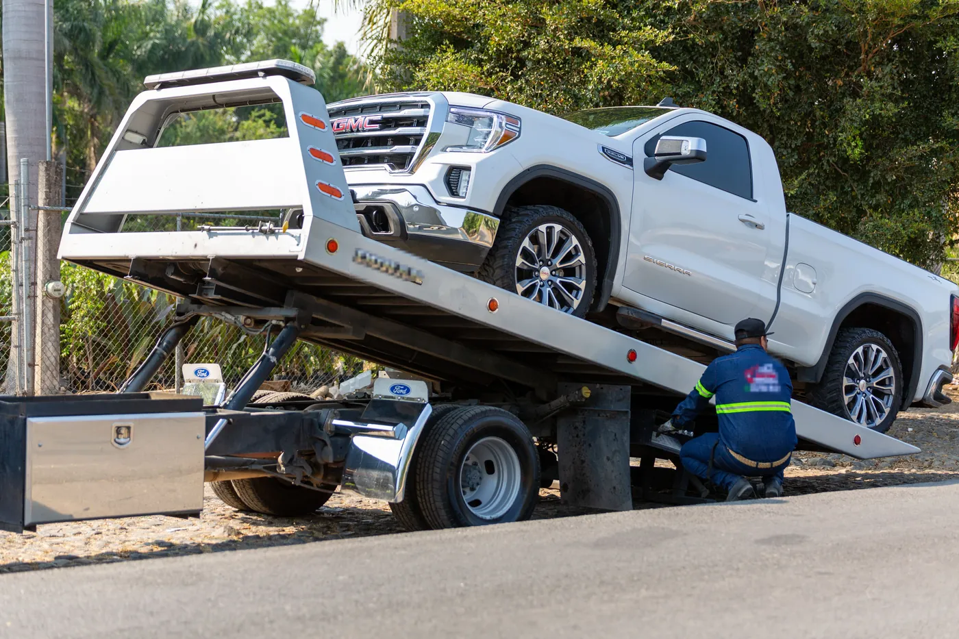 A pickup truck being loaded onto a tilted flatbed tow truck