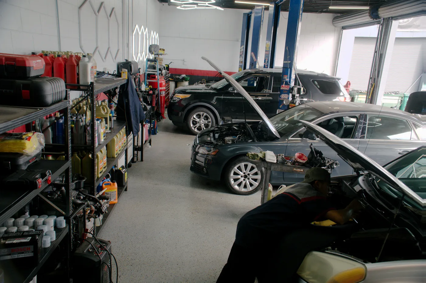 Inside the Bay Motors workshop, two cars with their hoods up and a technician at work