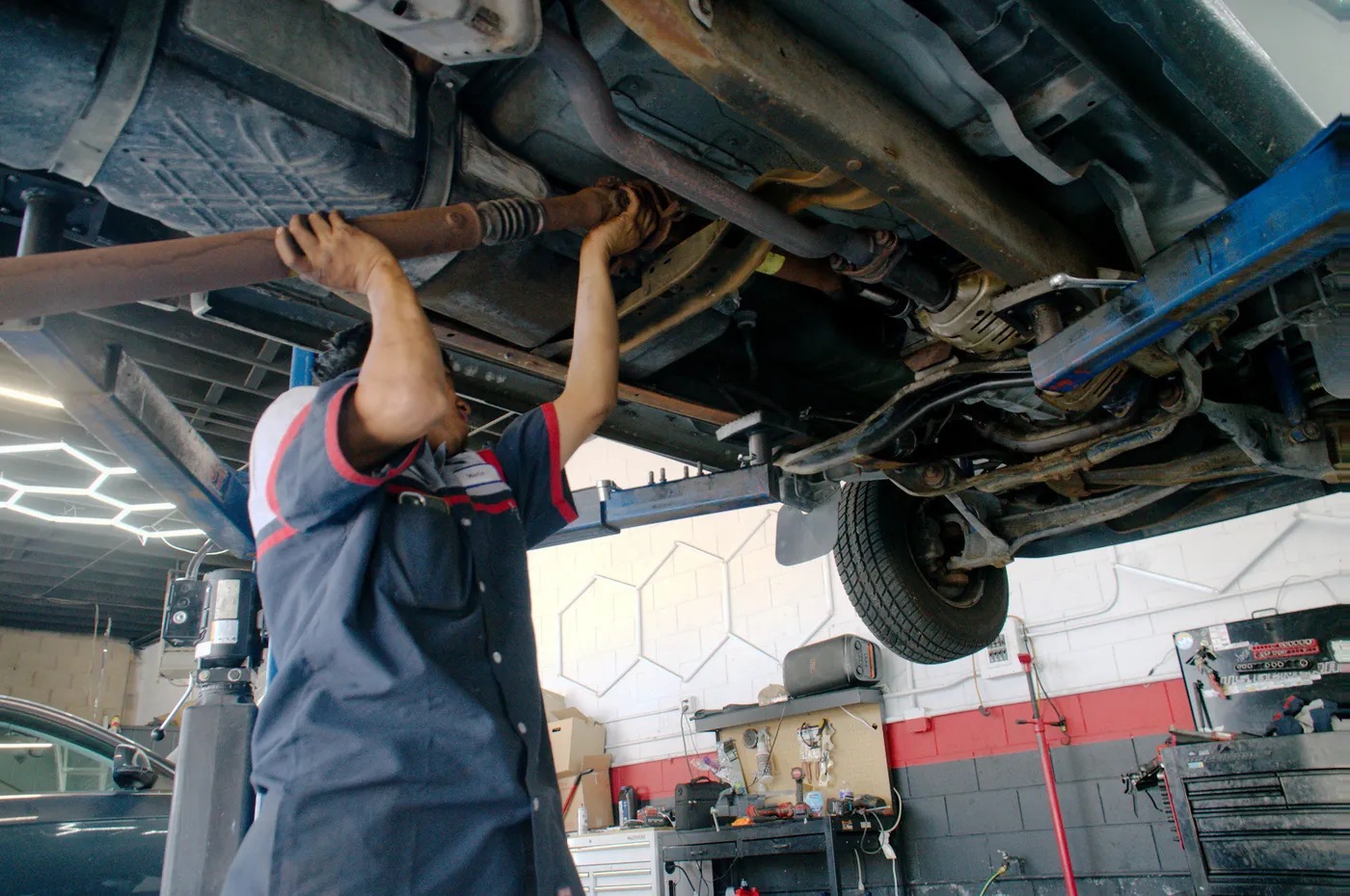 A technician working under a car raised on the lift